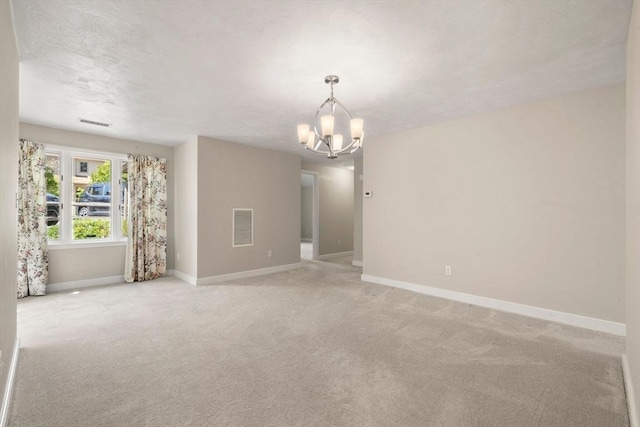 empty room with a chandelier, baseboards, visible vents, and light carpet