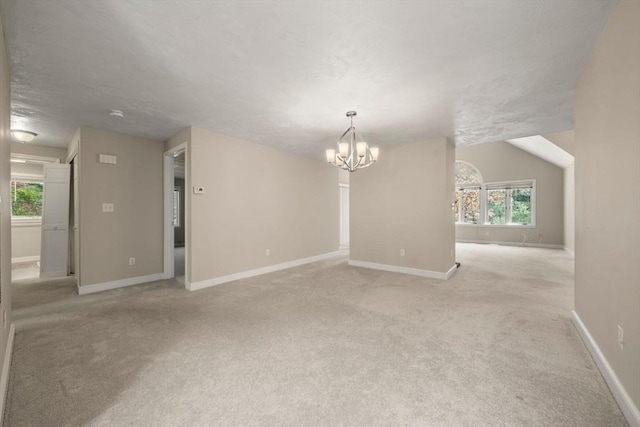 interior space with a chandelier, light carpet, and baseboards