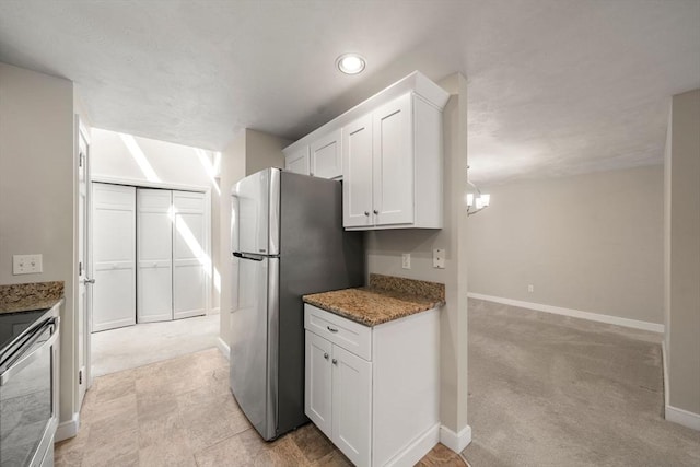 kitchen with stone countertops, white cabinetry, baseboards, light colored carpet, and appliances with stainless steel finishes