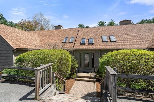 view of front of property with a shingled roof and a chimney