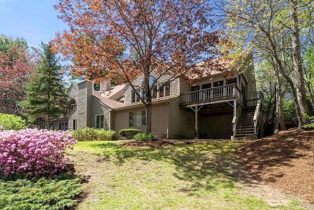 back of house featuring stairway, a deck, and a lawn