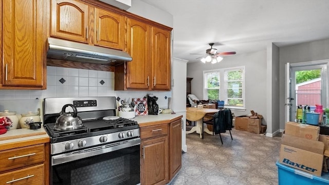 160-162 Rockland St, Fall River, MA 02724 - kitchen with stainless steel gas stove, under cabinet range hood, brown cabinets, ceiling fan, and decorative backsplash