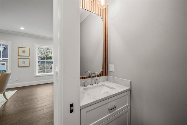bathroom with vanity, ornamental molding, wood finished floors, baseboards, and recessed lighting