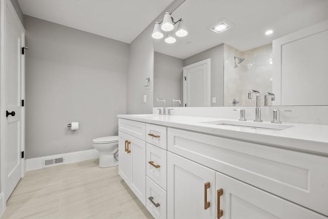 full bath with a sink, a tile shower, toilet, and double vanity