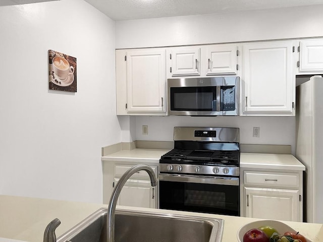 kitchen with appliances with stainless steel finishes, sink, and white cabinets