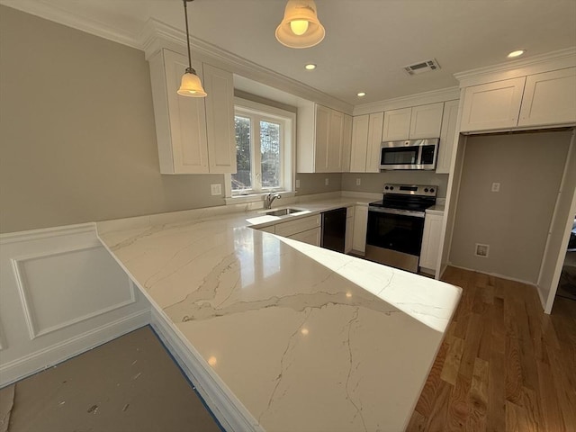 kitchen featuring light stone counters, pendant lighting, stainless steel appliances, crown molding, and white cabinetry