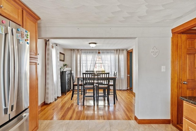 dining room with ornamental molding, light wood finished floors, and baseboards