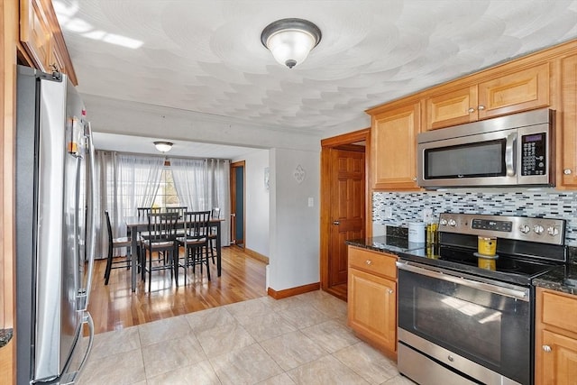 kitchen with stainless steel appliances, decorative backsplash, ornamental molding, and baseboards
