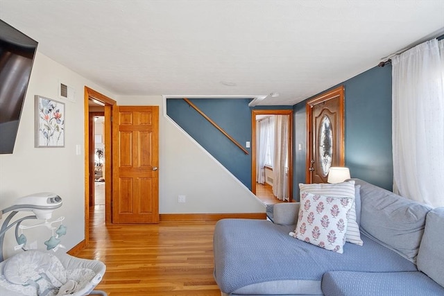 living room featuring stairs, visible vents, baseboards, and light wood-style floors
