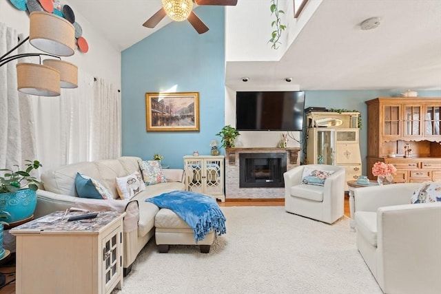 living area featuring vaulted ceiling, a glass covered fireplace, and a ceiling fan