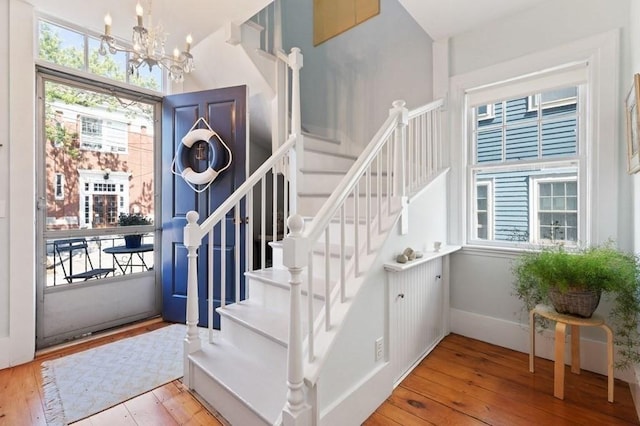 foyer entrance featuring stairs, wood-type flooring, and a chandelier