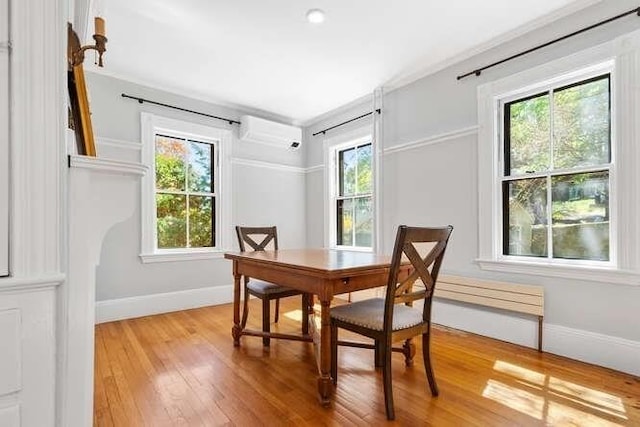 dining space with an AC wall unit, baseboards, a wealth of natural light, and light wood-style floors