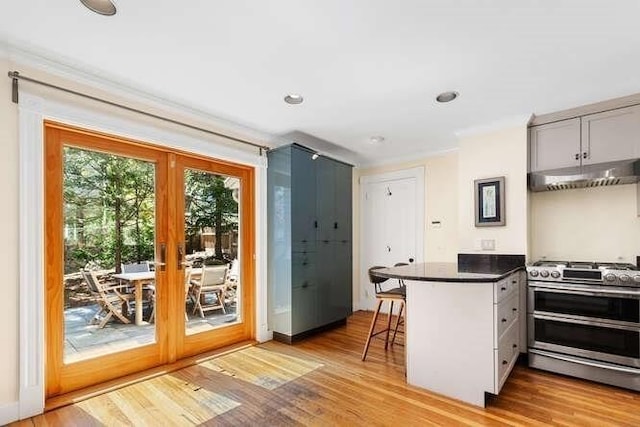 kitchen with french doors, under cabinet range hood, double oven range, and a kitchen bar