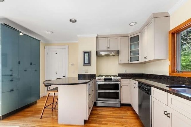 kitchen with crown molding, a peninsula, appliances with stainless steel finishes, and a kitchen bar