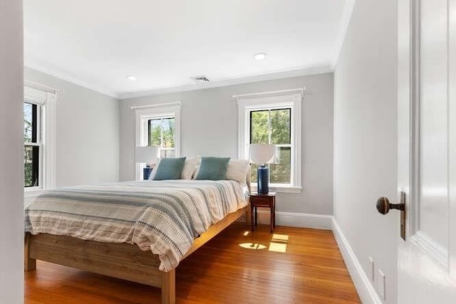 bedroom featuring crown molding, baseboards, visible vents, and light wood-style flooring