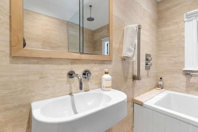 bathroom featuring a sink, tile walls, a bathing tub, and a shower