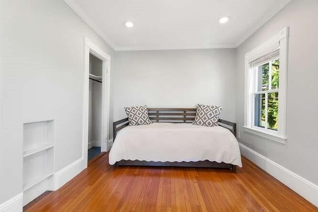bedroom with recessed lighting, baseboards, ornamental molding, and wood finished floors