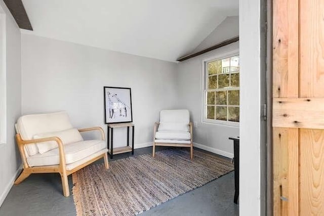 living area with concrete flooring, baseboards, and lofted ceiling
