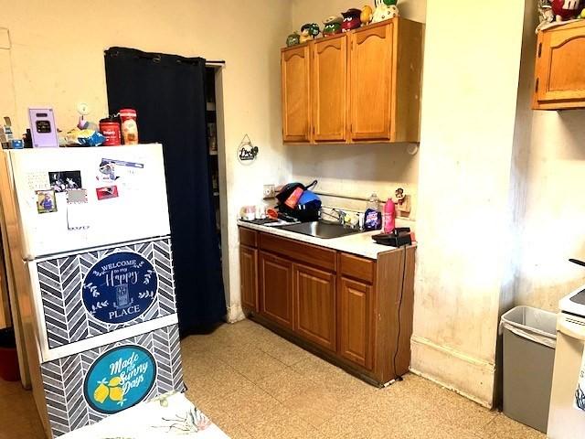 40 Byers St, Springfield, MA 01105 - kitchen with light countertops, light flooring, brown cabinets, and freestanding refrigerator