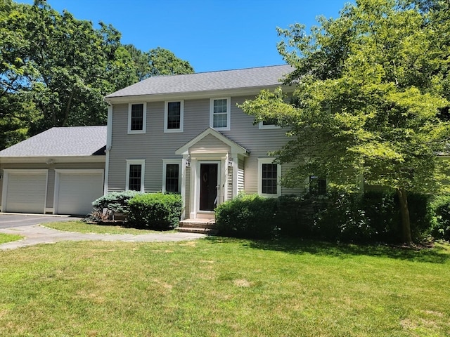 colonial house featuring a garage and a front lawn