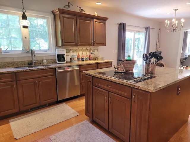 kitchen featuring decorative light fixtures, sink, stainless steel dishwasher, electric cooktop, and light hardwood / wood-style flooring