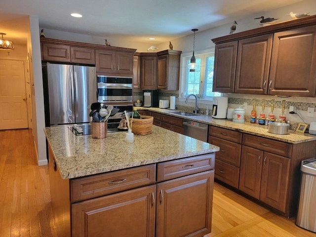 kitchen with a center island, appliances with stainless steel finishes, sink, and light hardwood / wood-style flooring