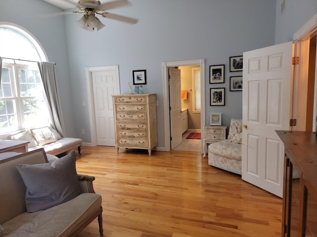 living area featuring a high ceiling, ceiling fan, and light hardwood / wood-style flooring