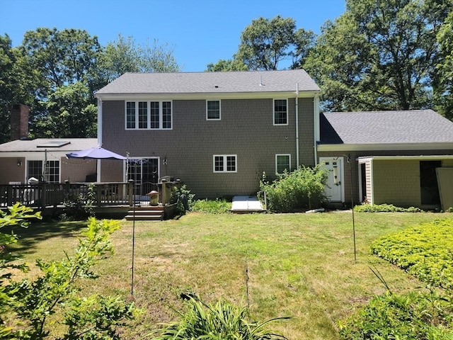 back of property featuring a wooden deck and a lawn