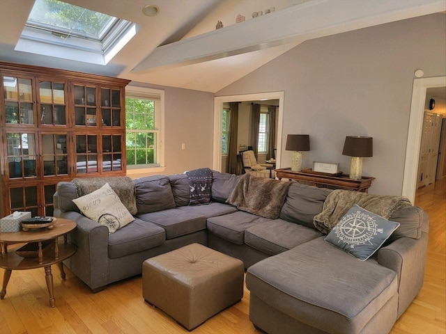 living room featuring vaulted ceiling with skylight and light wood-type flooring