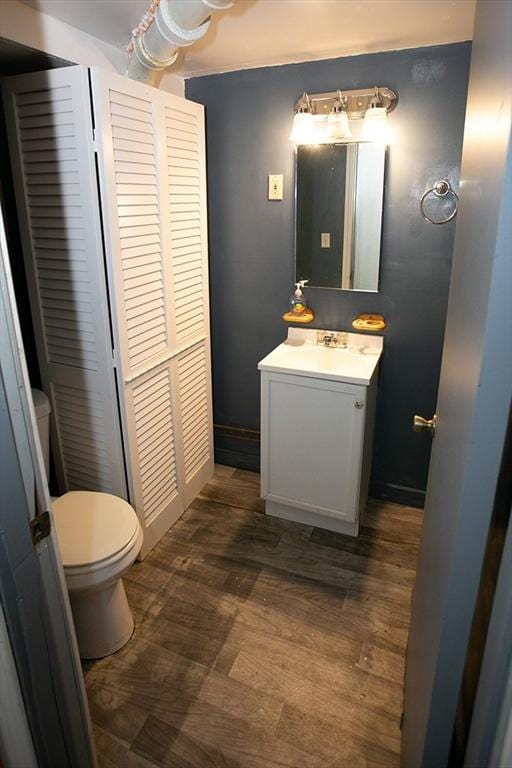 half bathroom featuring toilet, vanity, and wood finished floors