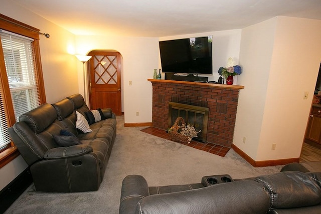 carpeted living room with arched walkways, a fireplace, and baseboards
