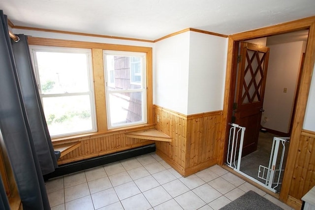interior space featuring wainscoting, wooden walls, crown molding, and light tile patterned flooring