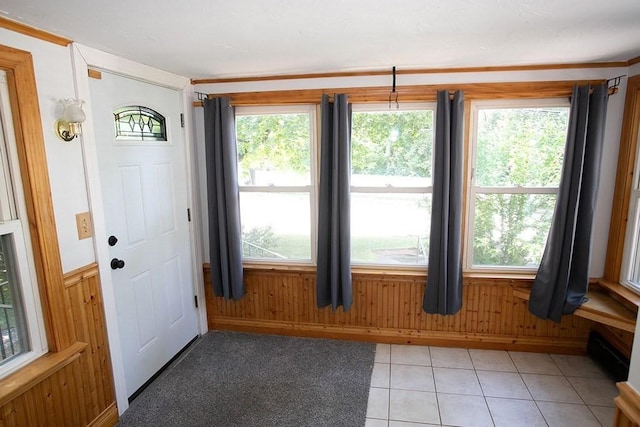 entryway featuring wooden walls, light tile patterned floors, and baseboards