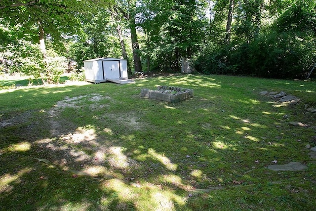 view of grassy yard with a storage unit, an outdoor structure, and a vegetable garden