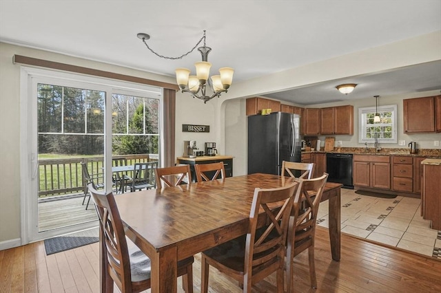 dining space with baseboards, an inviting chandelier, and light wood finished floors