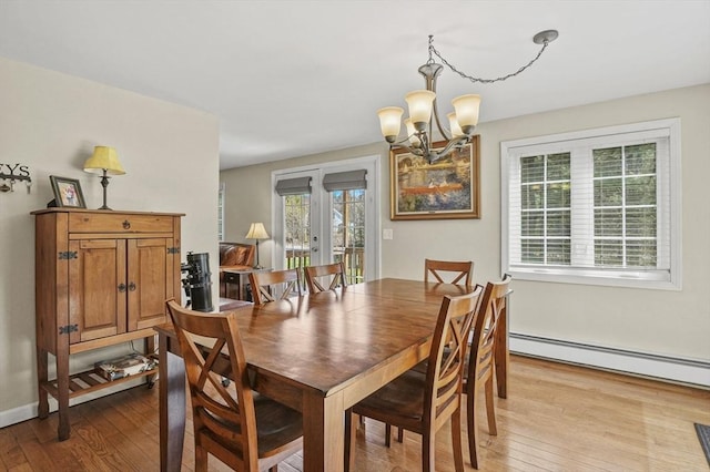dining room with hardwood / wood-style floors, a chandelier, a baseboard heating unit, and french doors