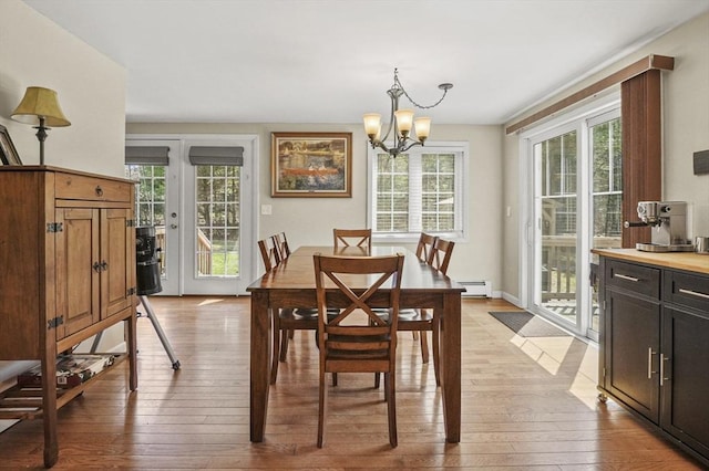 dining area featuring an inviting chandelier, a healthy amount of sunlight, light wood-type flooring, and baseboard heating
