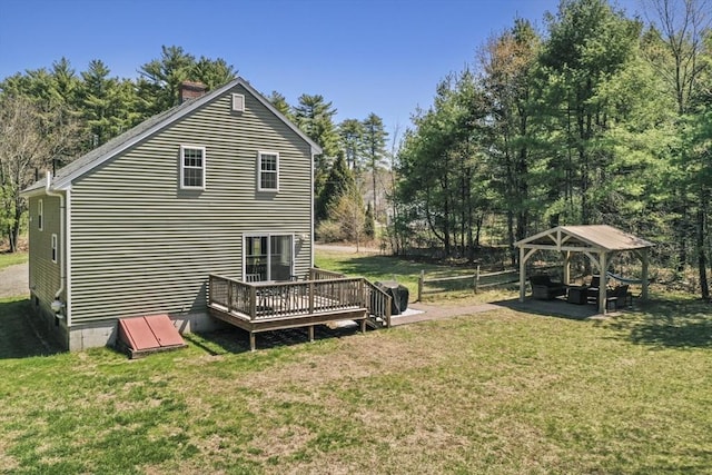 back of house with a wooden deck, a yard, fence, and a chimney