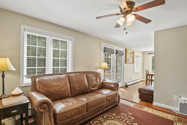 living room with ceiling fan, baseboard heating, wood finished floors, and baseboards