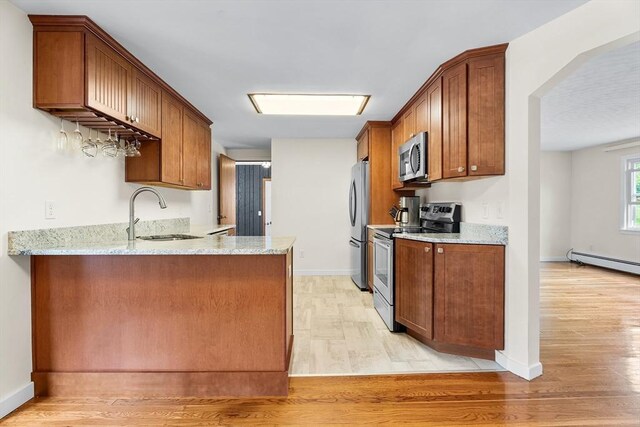 18 Fairview Rd, Westborough, MA 01581 - kitchen featuring appliances with stainless steel finishes, light wood-type flooring, light stone counters, and brown cabinetry