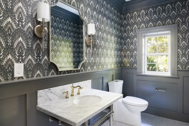 bathroom with ornamental molding, toilet, and sink