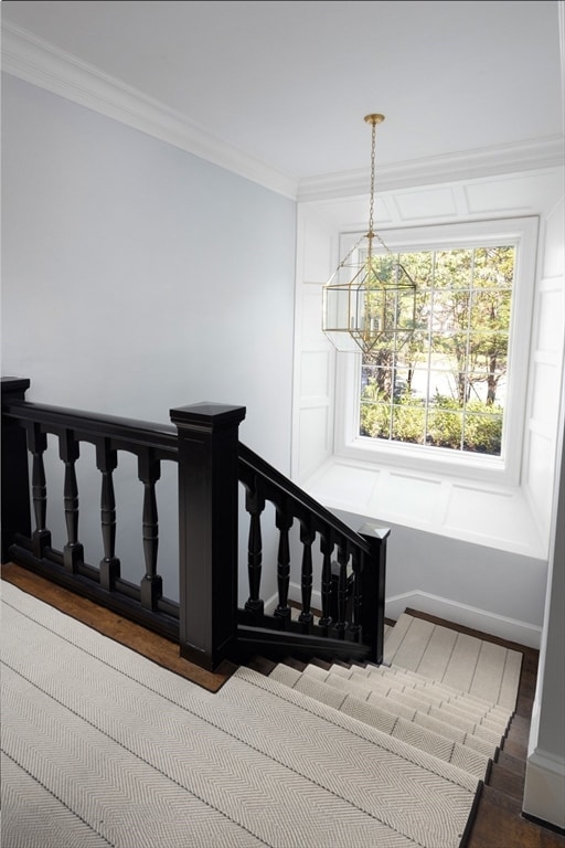 stairs with an inviting chandelier, hardwood / wood-style floors, and crown molding