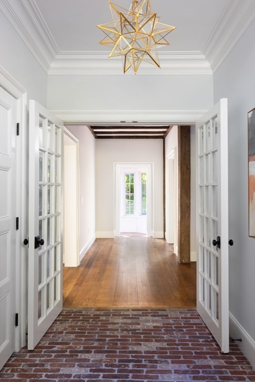 hall with dark wood-type flooring, a chandelier, french doors, and crown molding