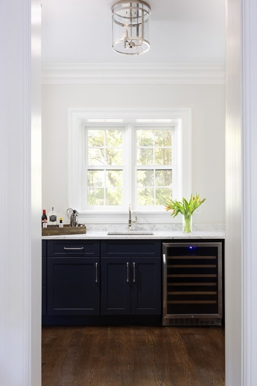 bar featuring wine cooler, a chandelier, dark wood-type flooring, sink, and ornamental molding