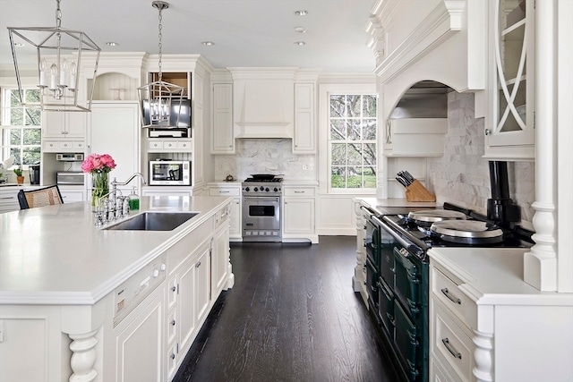 kitchen featuring an island with sink, backsplash, custom range hood, and stainless steel appliances