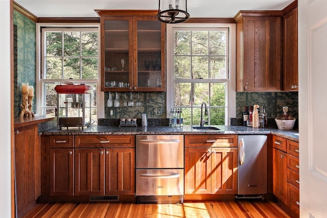 interior space featuring decorative light fixtures, a healthy amount of sunlight, light hardwood / wood-style flooring, and tasteful backsplash