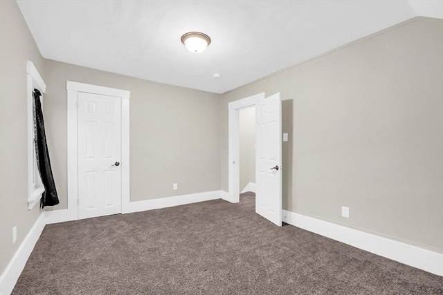 unfurnished bedroom featuring vaulted ceiling, dark carpet, and a closet