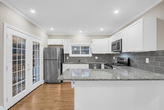 kitchen with light stone counters, kitchen peninsula, appliances with stainless steel finishes, and french doors