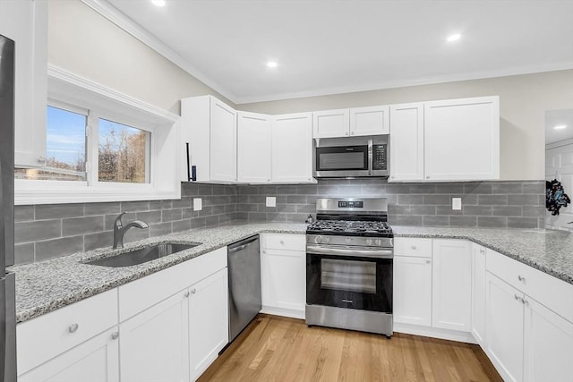 kitchen featuring decorative backsplash, sink, white cabinets, and appliances with stainless steel finishes