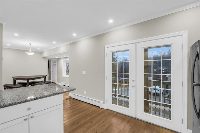 kitchen featuring stone counters, hanging light fixtures, baseboard heating, hardwood / wood-style floors, and white cabinets